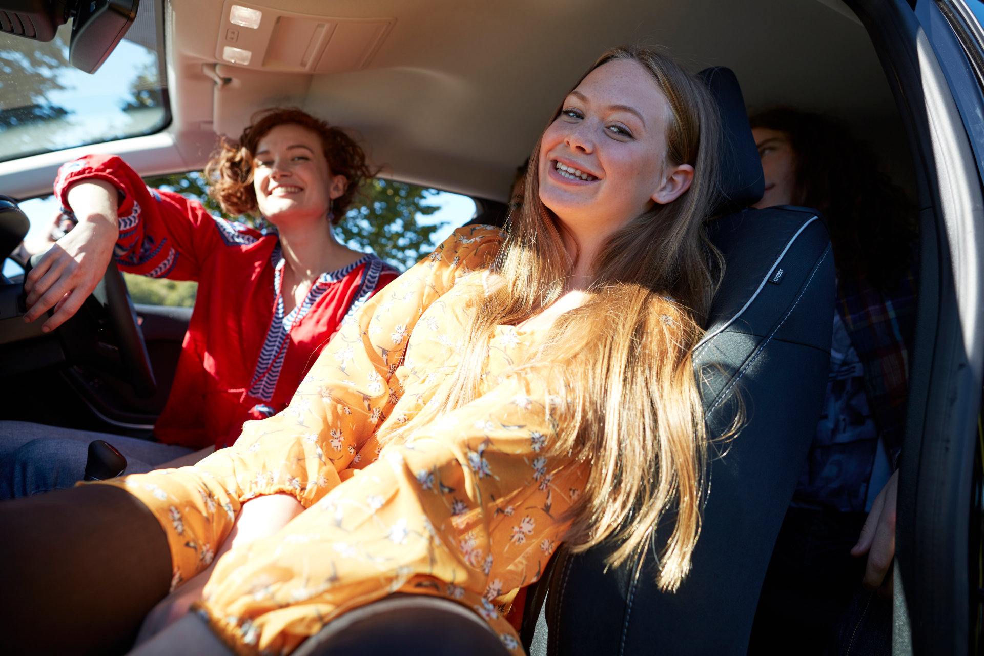 Four young people sitting in a car, smiling