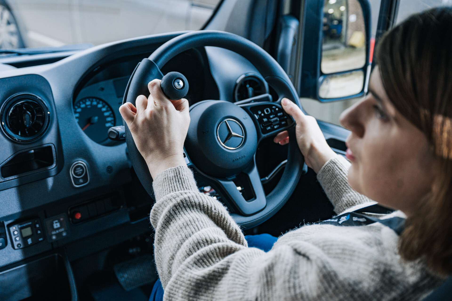 A woman using a steering wheel aid adaptation while driving