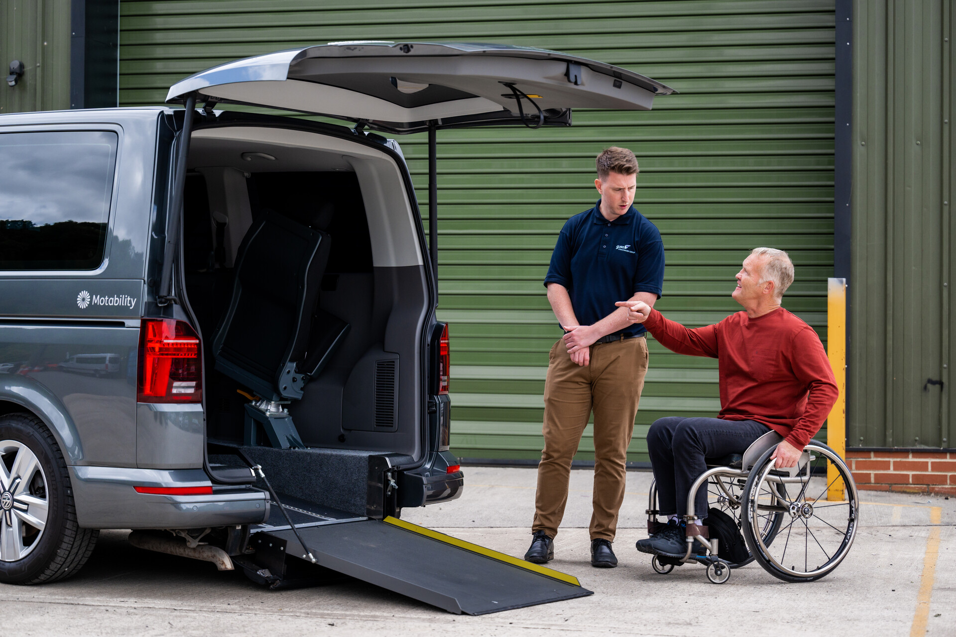 A WAV supplier shows a man how to use a ramp, on a Wheelchair Accessible Vehicle