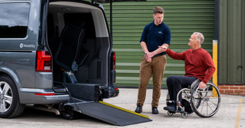 A WAV supplier shows a man how to use a ramp, on a Wheelchair Accessible Vehicle