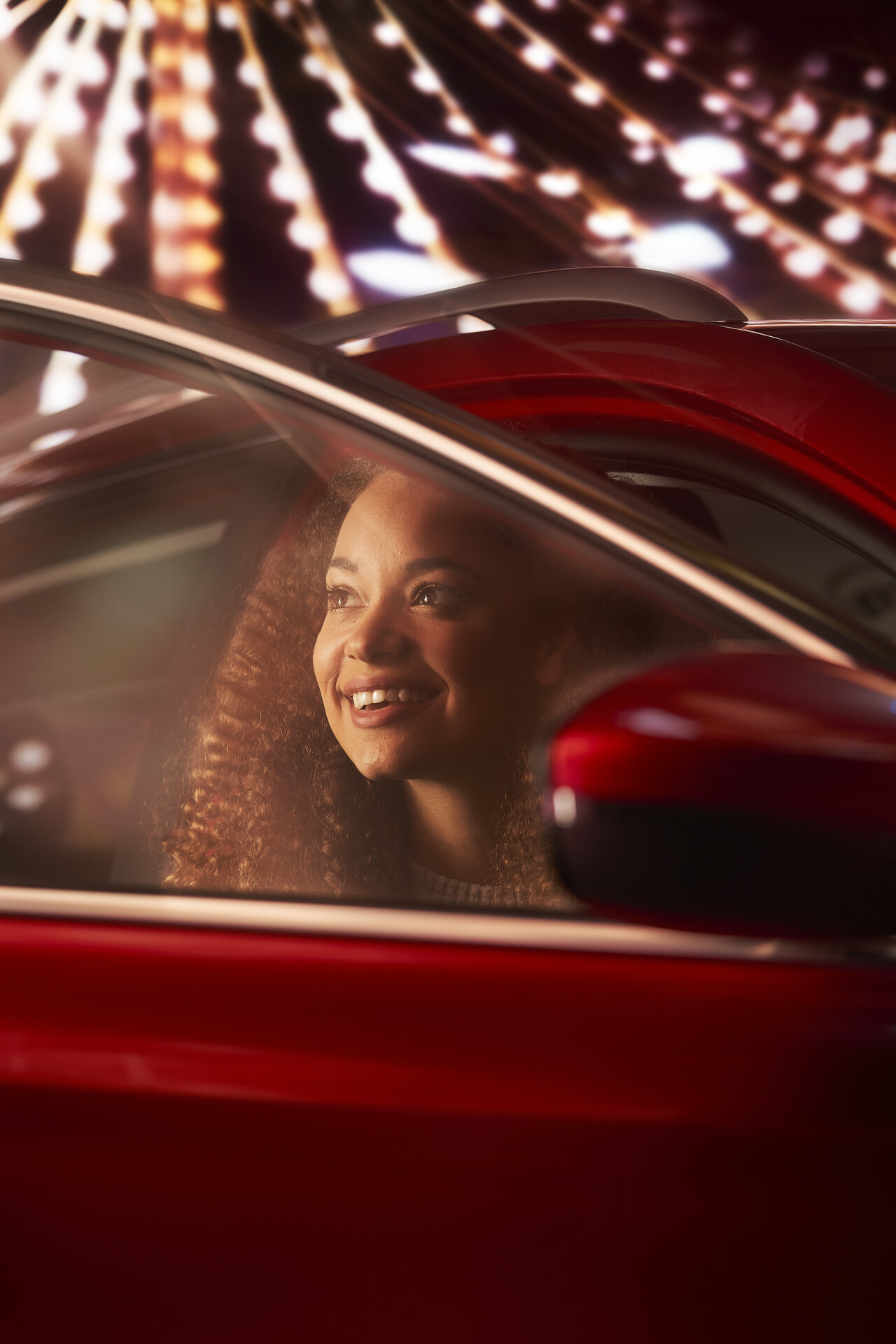 A woman smiling as she gets out of a car, at night