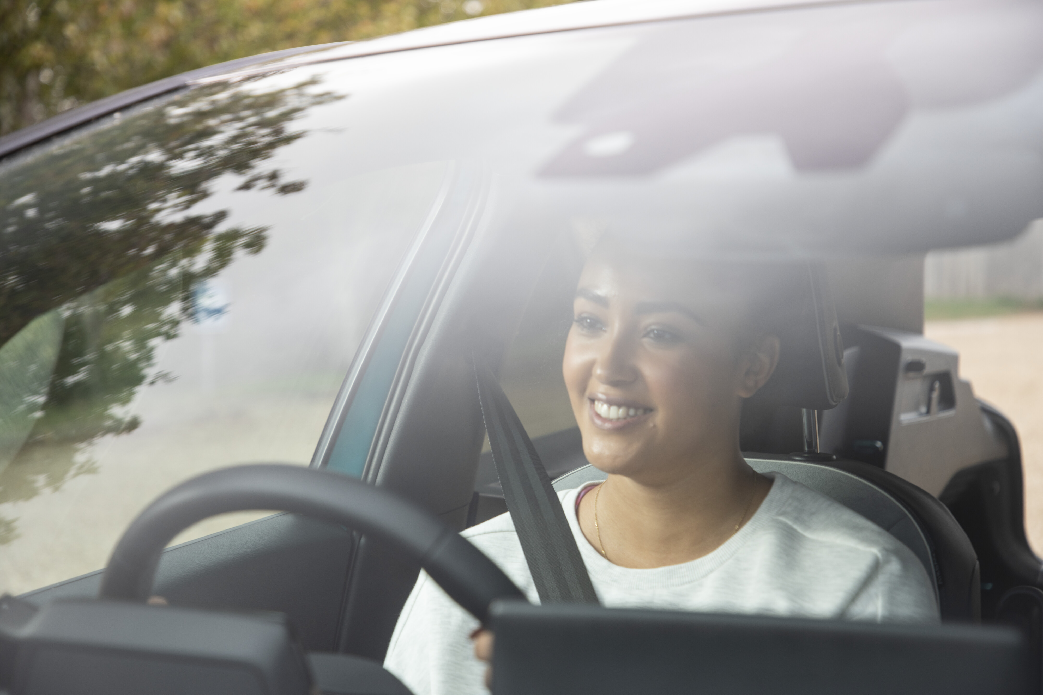A woman smiling and driving a car