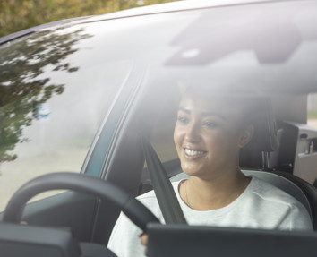 A woman smiling and driving a car