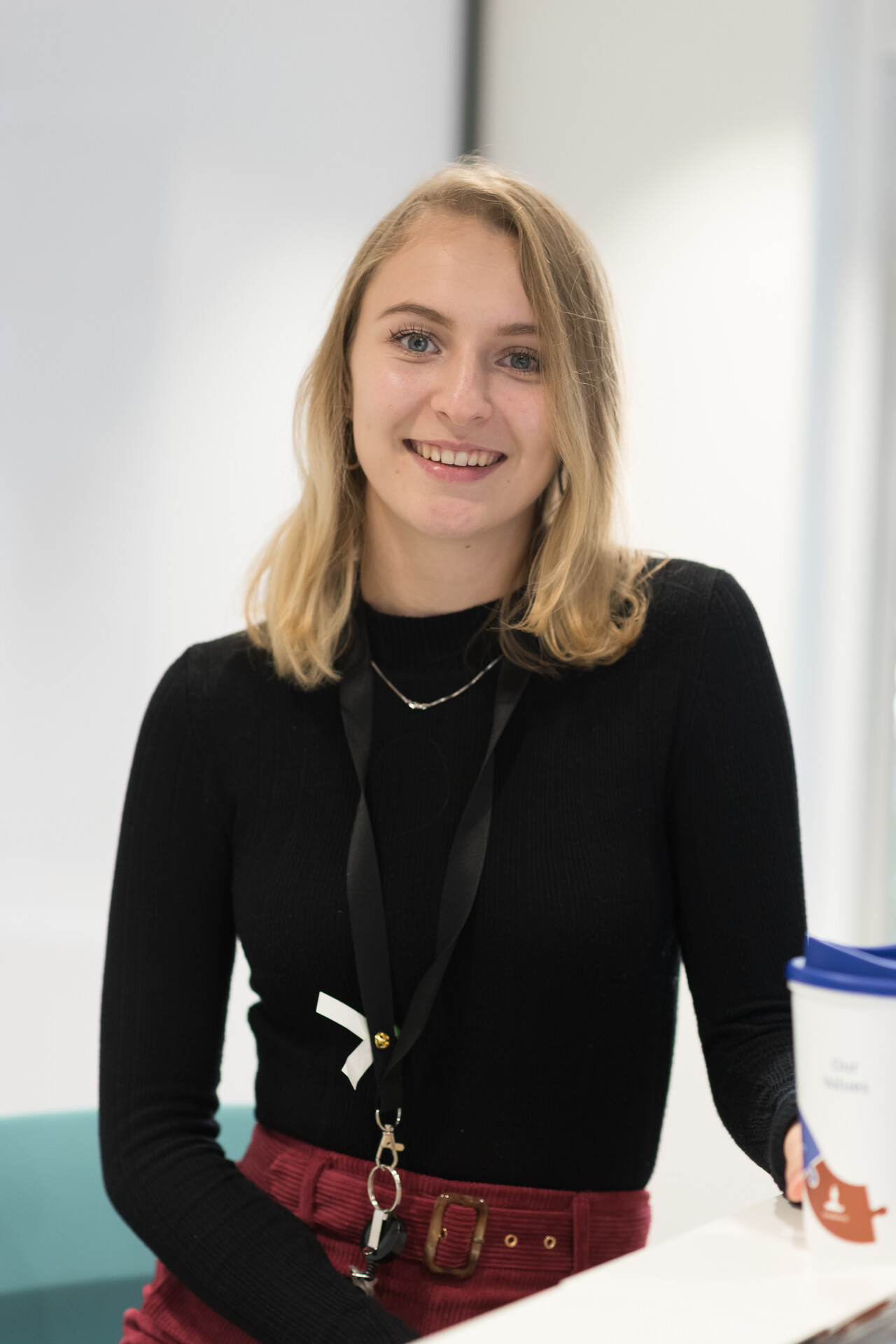 A young woman in an office looking into the camera and smiling