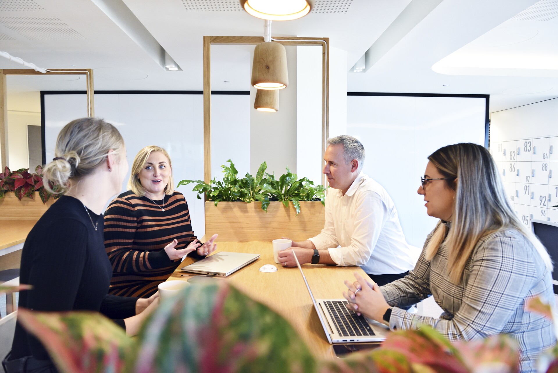 Three women and one man chat in an office