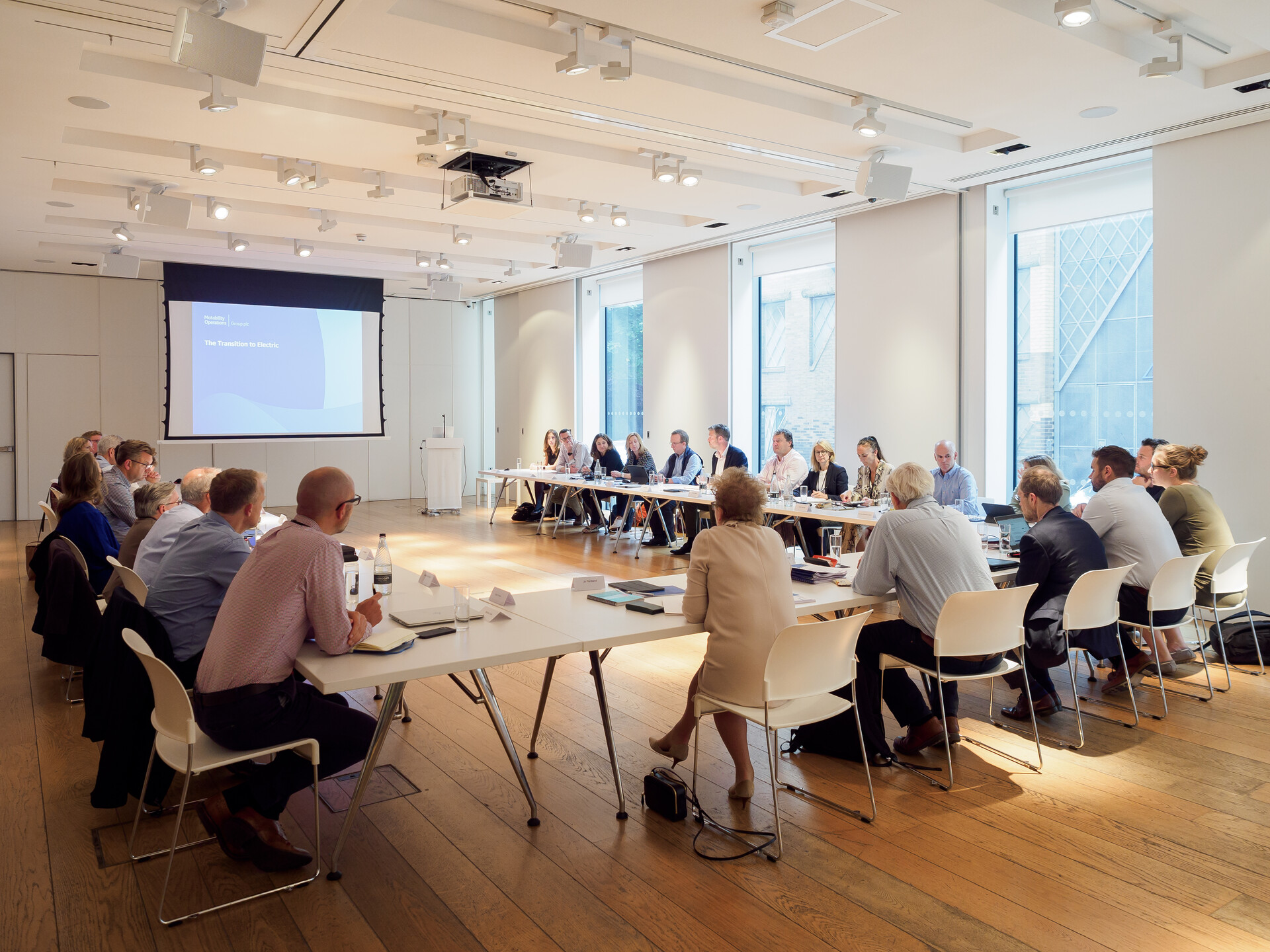 A room of people, sat down looking at a presentation