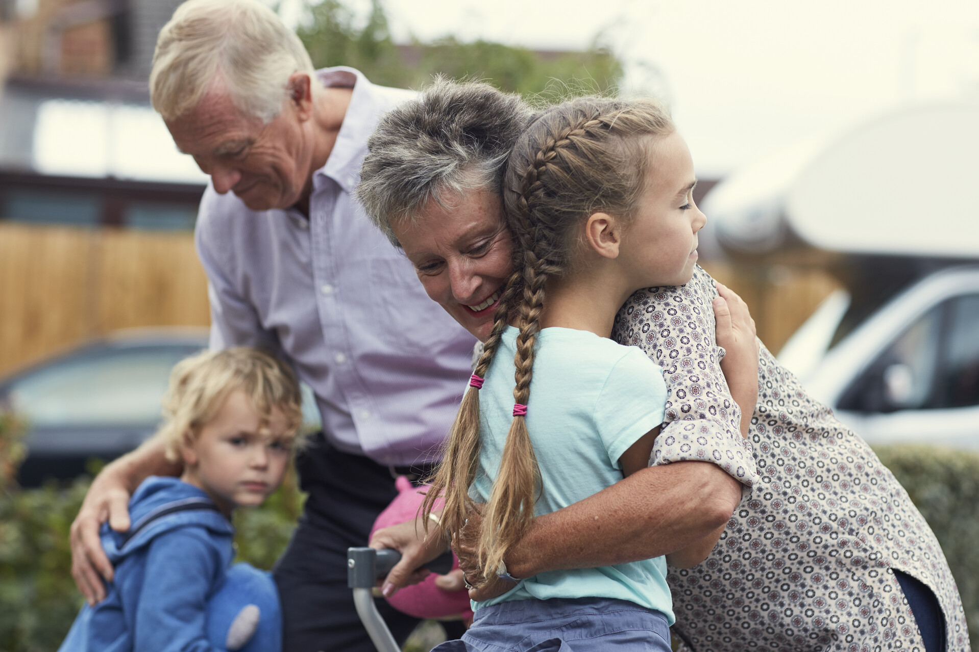 Grandparents hug their two grandchildren, a boy and a girl